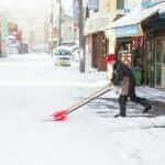 A man using shovel to removes snow and clear the road after snowfall, hakodate, Japan = Shutterstock