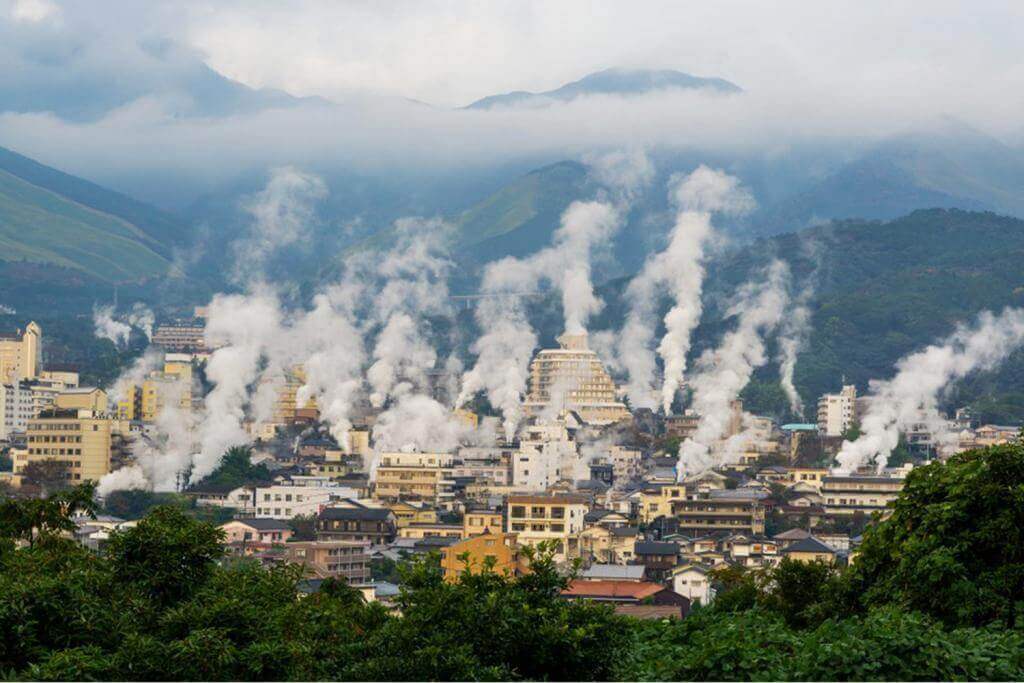 Beautiful scenery of Beppu cityscape with Steam drifted from public baths and ryokan onsen. Beppu is one of the most famous hot spring resorts in Japan, Oita, Kyushu, Japan = Shutterstock