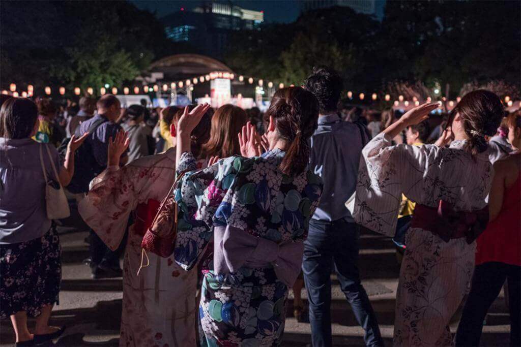 Crowd of people dancing at a Bon Odori festival in Hibiya Park, Japan = Shutterstock