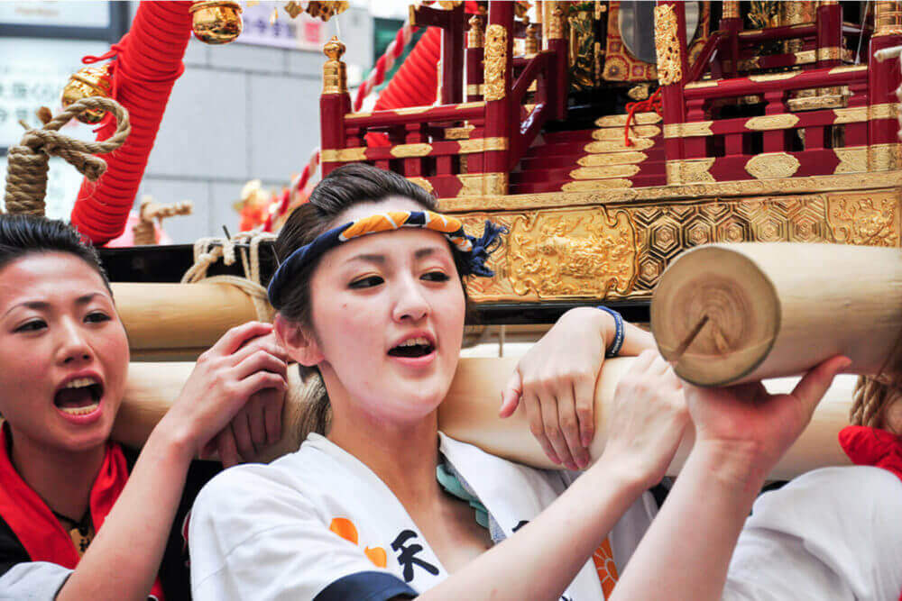 Facial shot of unidentified young women worshipping the golden shrine in Tenjin Matsuri, Osaka's biggest festival = Shutterstock