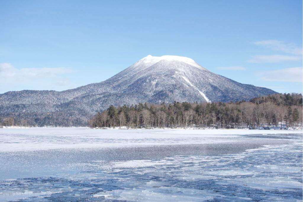Frozen Lake Akan, Hokkaido. Lake Akan was born from the eruption of a volcano. It is surrounded by Mount Meakan and Mount Oakan = SHutterstock