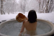 Japanese woman in an open air hot onsen bath = Shutterstock