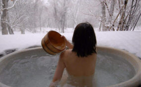 Japanese woman in an open air hot onsen bath = Shutterstock