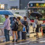 People lining up for the bus during a rainy night at Shibuya station. The rainy season, locally known as tsuyu or baiyu, begins the from June until mid July in Japan = Shutterstock