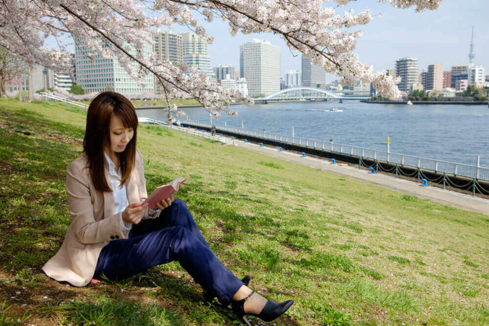 The woman who reads a book under the cherry tree = Shutterstock