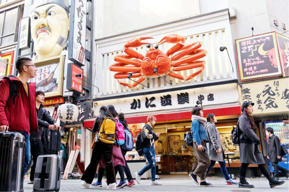 Tourists at Dotonbori walking street. Dotonbori is one of the principal tourist destinations in Osaka, Japan = Shutterstock