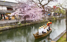 Unknown tourists are enjoying the old-fashioned boat along the Kurashiki canal in Bikan district of Kurashiki city, Japan = Shutterstock