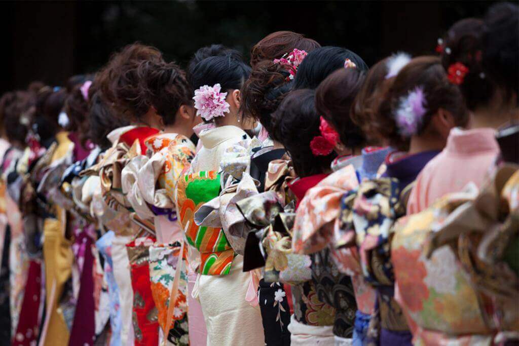 Young Japanese women wearing kimonos for the coming of age, to celebrate the year they turn twenty = Shutterstock