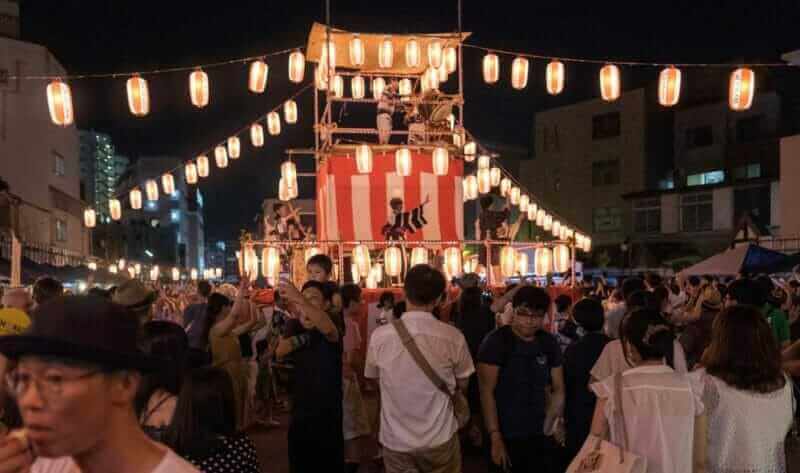 Crowd of people at the Bon Odori celebration in Shimokitazawa neighborhood at night.