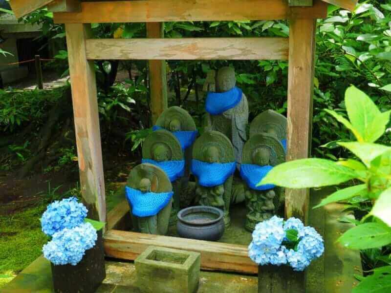 JIzo with blue bib in Meigetsuin temple Kanagawa,Japan = shutterstock