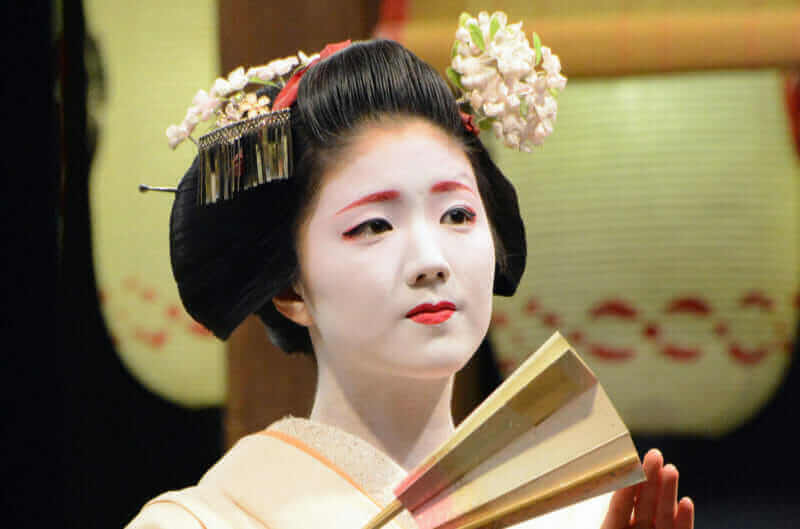 A Japanese geisha performs for a public event at a shrine in Kyoto = shutterstock
