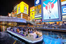 Touristic boat in Dotonbori Canal and famous Glico Running Man sign in Dotonbori street, Namba, a popular shopping and entertainment district., Osaka, Japan = Shutterstock