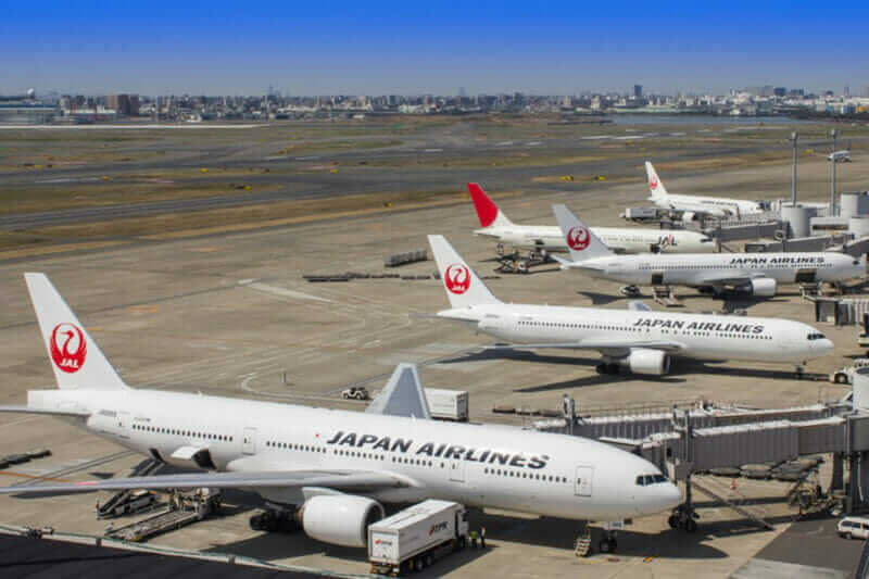 White and red Japan Airlines (JAL) Boeing 777 Dreamliner passenger planes are prepared for takeoff at the terminal building of Tokyo International Airport = shutterstock
