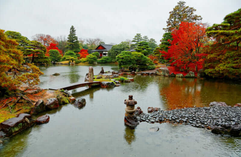 Autumn scenery of a beautiful Japanese garden in Katsura Imperial Villa ( Royal Park ) in Kyoto, Japan, with view of fiery maple trees by the lake and a stone bridge over the pond on a rainy day = shutterstock