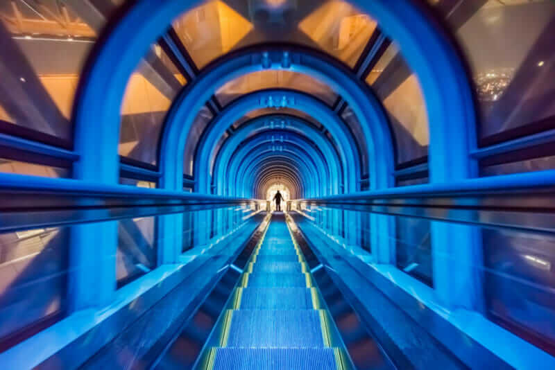 Modern tunnel escalator with traveler at Umeda Sky Building. It is a futuristic moving electric staircase for vertical transportation = shutterstock