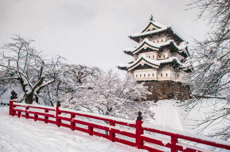 White Hirosaki Castle and its red wooden bridge in mid winter season, Aomori, Tohoku, Japan = shutterstock