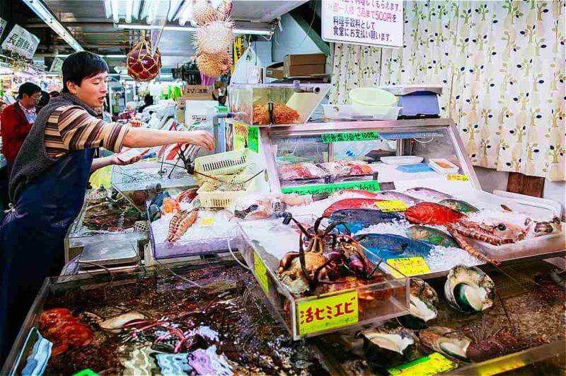 Local fish and seafood shop with customers in Makishi Public Market = shutterstock