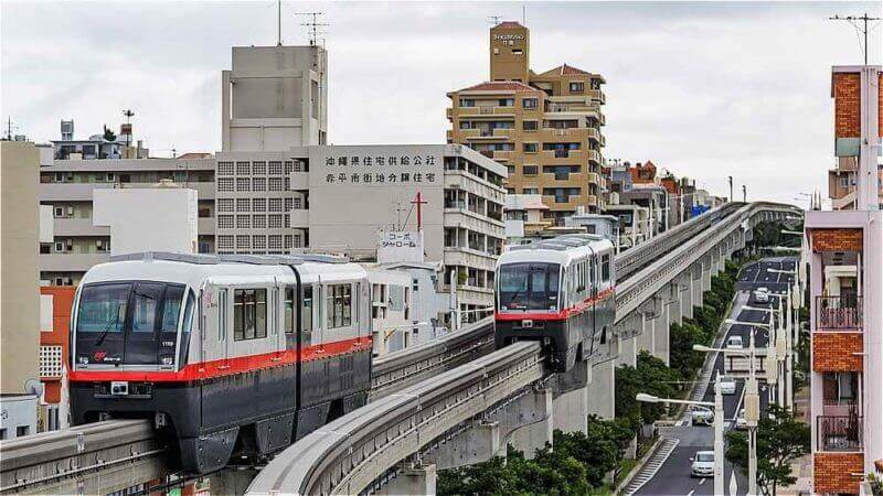 Two Okinawa Monorail 1000 series trains passing at Gibo Station in Naha, Okinawa, Japan = shutterstock_11704550411