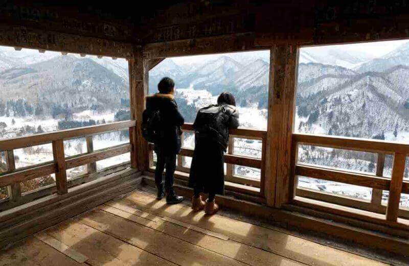 Tourists enjoy the panorama overlooking the winter mountains from Godaido Hall viewpoint, one of the historical wooden architectures in Risshaku-ji Buddhist Temple in Yamadera, Yamagata, Tohoku, Japan = shutterstock