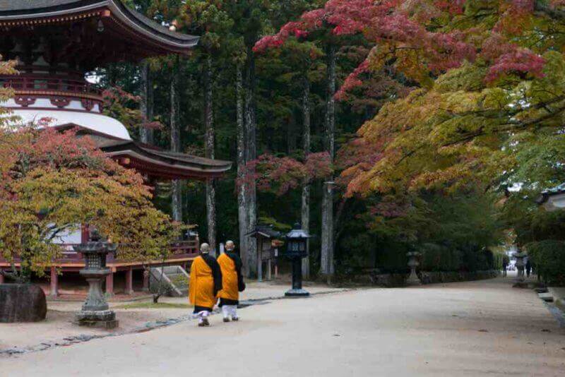 Buddhist monks walking past temple in Koyasan, Mt Koya, Japan during autumn = shutterstock