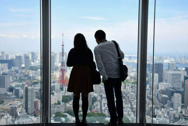 Tokyo couple lover with cityscape with Tokyo tower viewings from roof top of the roppongi hill tower, Tokyo = Shutterstock