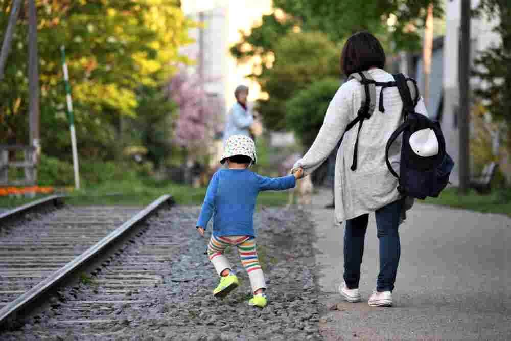MAY 20,2017: Mother and son walking back home with train railway background, Otaru, Hokkaido