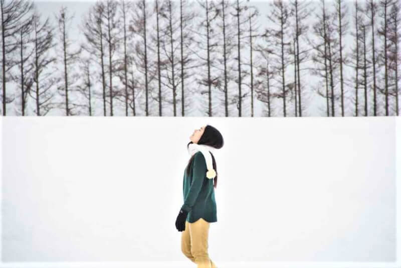 Green and yellow cloth Woman on pine trees and white snow background = Shutterstock