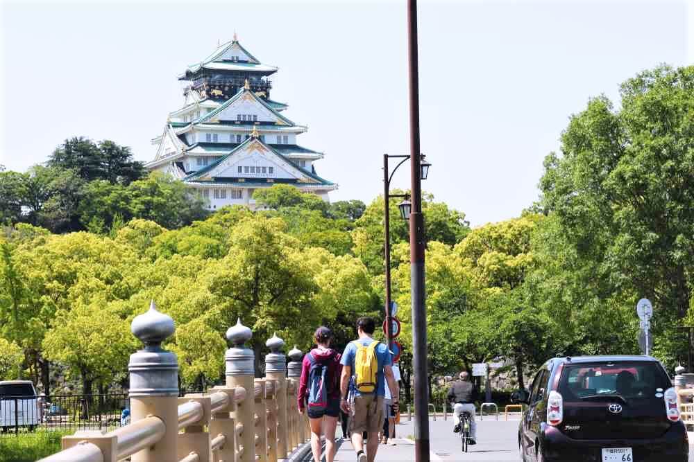 MAY 5, 2018: Two foreign tourists walking over the old historical bridge to entry the Osaka Castle, Osaka, Japan =Shutterstock