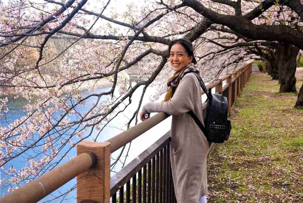April 11, 2019: Woman along the canal outside Osaka Castle and Cherry blossoms bloom a lot at Osaka Castle, Osaka, Japan = Shutterstock