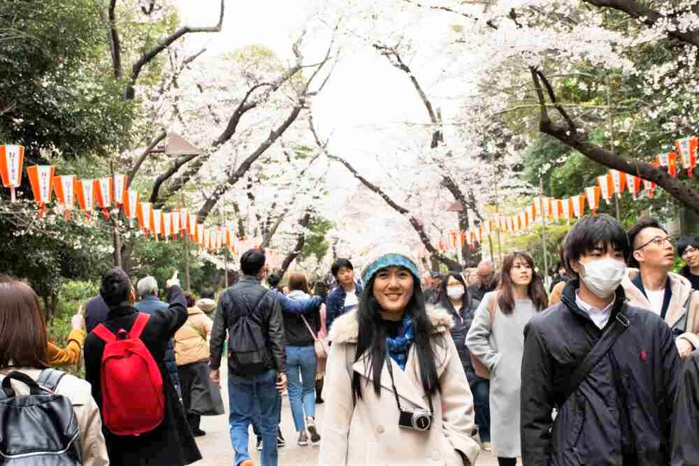 MARCH 30 : Thai women people posing portrait for take photo with japanese people and foreign travelers walk looking sakura flowers at Ueno public park on March 30, 2019 in Tokyo, Japan = Shutterstock