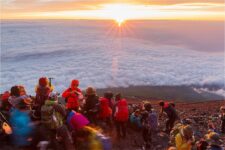 Climbers watching the sunrise at the top of Mt. Fuji = Shutterstock