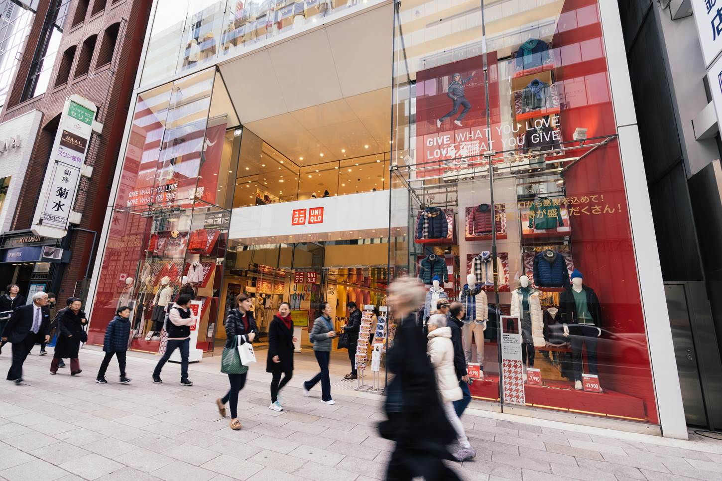 People and tourists walking and shopping in front of Uniqlo famous Japanese clothing represent modern consumerism = Shutterstock